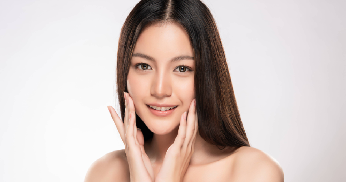 Woman with glowing skin smiling and gently touching her face after skin rejuvenation treatment in Chattanooga